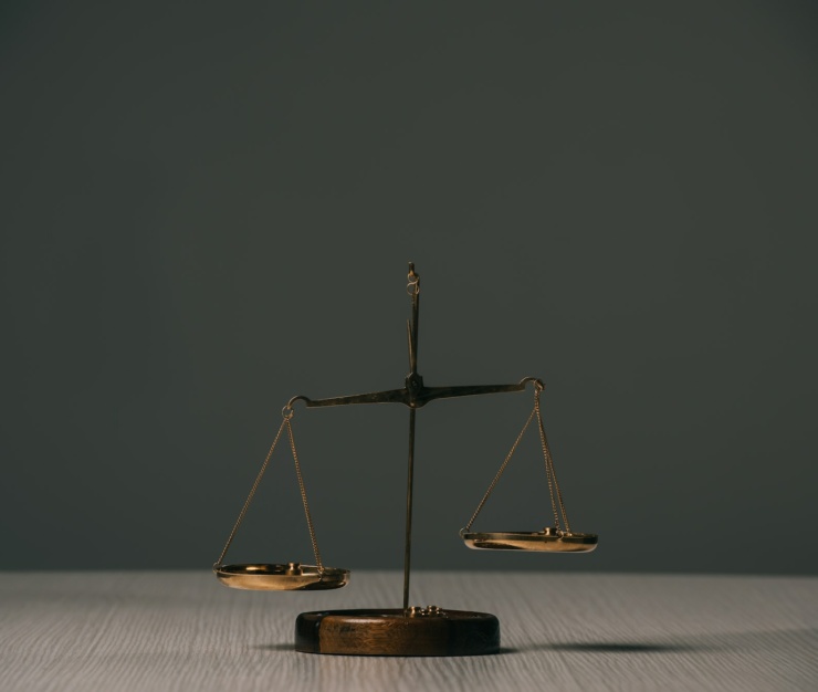 empty scales of justice on wooden table on grey