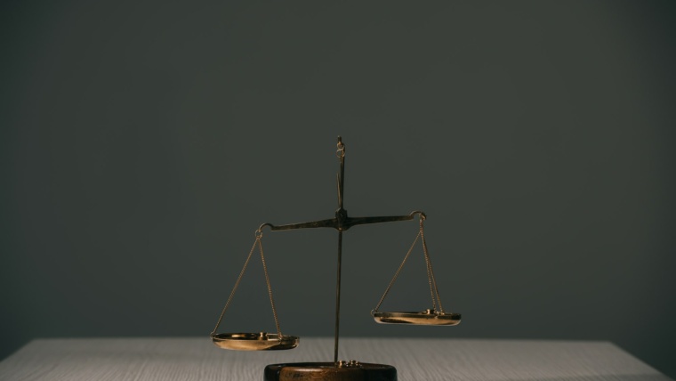 empty scales of justice on wooden table on grey